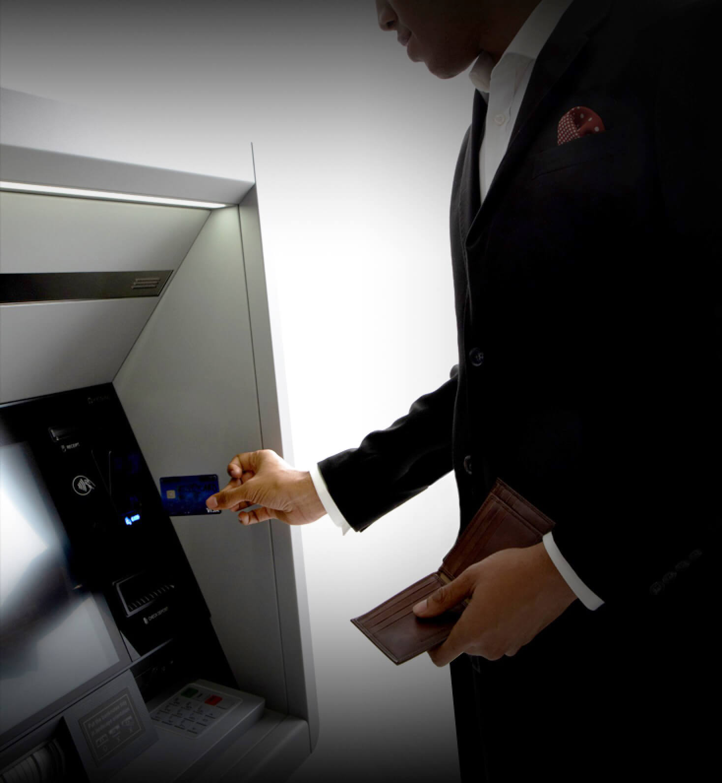 Man wearing suite using card at ATM